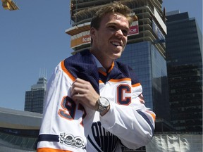 Connor McDavid pulls on the Edmonton Oilers' new away jersey at a construction site in downtown Edmonton's Ice District on July 5, 2017, following a media conference annoucning his eight-year contract extension with the NHL club worth $12.5-million per season.
