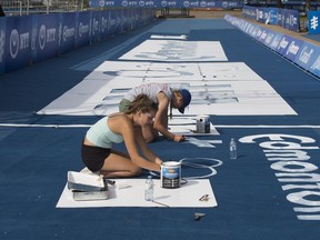 Kennedy Barber (left) and Halle Nanninga paint logos on the finish line as crews set up for the ITU World Triathlon Edmonton in Hawrelak Park in Edmonton on Thursday July 27, 2017.