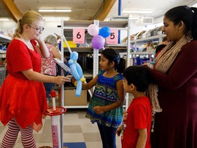 Balloon artist Chanel Brown hands a balloon to Iha Nair, 8, during the Reuse Centre's 10th anniversary in Edmonton on Saturday. (Codie McLachlan/Postmedia)