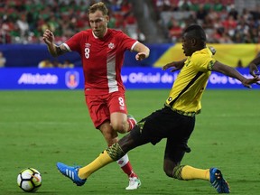 Canada's Scott Arfield, left,is tackled by Jamaica's Cory Burke during their quarterfinal match of the 2017 CONCACAF Gold Cup at the University of Phoenix Stadium on July 20, 2017 in Glendale, Arizona. Jamaica won 2-1.