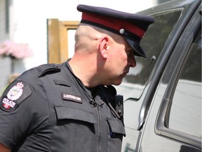 Const. John Kitchen, with the Edmonton Police southeast division neighbourhood foot patrol, peers through windows looking for easy targets of crime in a back alley in Bonnie Doon in Edmonton, Alta. on Thursday, July 27, 2017.