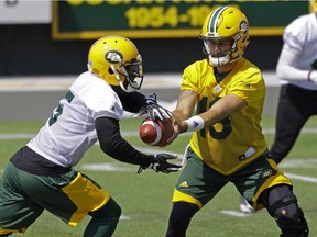 Edmonton Eskimos running back Travon Van (left) takes the ball from quarterback Mike Reilly during team practice at Commonwealth Stadium in Edmonton on July 10, 2017.