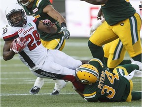 Ottawa Redblacks' William Powell (29) is tackled by Edmonton Eskimos' Garry Peters (34) during first half CFL action in Edmonton, Alta., on Friday July 14, 2017.