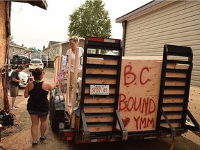 Crystal Purcell, 32, gives a handful of gift cards to Tamara Laverdiere, 35, as they load a trailer with donated supplies intended for fire halls and evacuation centres in B.C., where wildfires are spreading quickly. The trailer will hold supplies ranging from water and Gatorade to eye drops and sunscreen, in Fort McMurray, Alta. on Saturday, July 8, 2017. Cullen Bird/Fort McMurray Today/Postmedia Network.