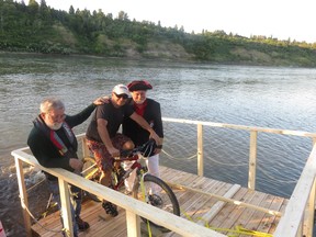 Sourdough Raft Race designer Roger Kehoe, left, Gord Laird, centre, and Nick Lees discuss modifications to their pedal-powered raft after it ran aground shortly after being launched Saturday night at the 50 Street boat launch.