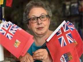Flag Shop owner Phyllis Bright holds samples of the Red Ensign flag in Edmonton, July 12, 2017.