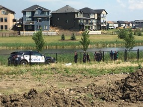 Edmonton Police Service officers speak with witnesses after a young girl was rescued from a man-made lake in the Crystallina Nera neighbourhood in the city's north on Saturday, July 22, 2017.