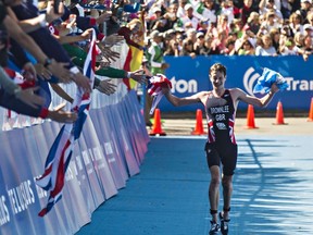 Great Britain's Alistair Brownlee greets fans as he approaches the finish in first place during the 2014 ITU World Triathlon Grand Final Edmonton elite men's race at Hawrelak Park in Edmonton, Alta., on Sunday, Aug. 31, 2014.