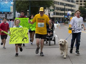 Roger MacMillan crosses the finish line with his grandchildren at the Edmonton Marathon on Sunday Aug. 20, 2017, in Edmonton. The 79-year-old runner completed his 100th marathon.