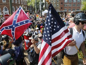 White nationalist demonstrators walk into Lee park surrounded by counter demonstrators in Charlottesville, Va., Saturday, Aug. 12, 2017. Gov. Terry McAuliffe declared a state of emergency and police dressed in riot gear ordered people to disperse after chaotic violent clashes between white nationalists and counter protestors. (AP Photo/Steve Helber)