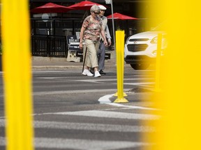 Pedestrians are framed by yellow lane markers as they cross Jasper Avenue at 111 Street on Aug. 23, 2017.