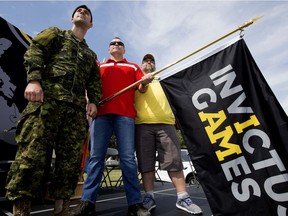 Invictus Games flag bearer Master Cpl. Joel Gagne, left, Invictus Games competitor Sgt. Lorne Ford and Invictus Games flag bearer Master Warrant Officer (retired) Mark DesRoches hold the Invictus Games flag at CFB Edmonton on Thursday, Aug. 24, 2017.