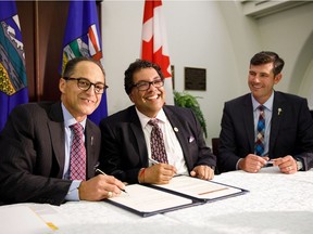 Alberta Finance Minister Joe Ceci, from left, Calgary Mayor Naheed Nenshi and Edmonton Mayor Don Iveson smile while signing a new charter as the provincial government reveals details of new city charters for Edmonton and Calgary at the Alberta legislature in Edmonton on Thursday, Aug. 10, 2017.