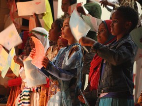 Children participating in a youth summer camp run by the Africa Centre in Edmonton dance together while waving flags from their families' countries of origin at Kameyosek School on Thursday, Aug. 10, 2017.