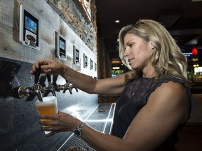Heather Seale pours herself a Beaver Tail Raspberry Ale from Canmore at Alberta's first self-serve beer and wine wall in Barney's Pub and Grill in Leduc on Aug. 2, 2017. The wall features a rotating mix of 12 Alberta craft beers and two wines. Plastic cards limit the patrons to 32 ounces of beer before the card shuts down.