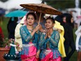 Wanida Phathip, left, and Ketsara Sungnhoung, right, take shelter under an umbrella during the Heritage Festival in Edmonton on Saturday, Aug. 5, 2017.