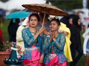 Wanida Phathip, left, and Ketsara Sungnhoung, right, take shelter under an umbrella during the Heritage Festival in Edmonton on Saturday, Aug. 5, 2017.