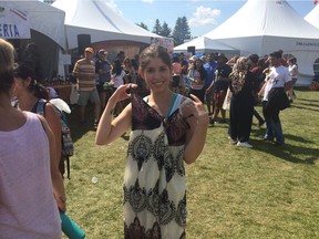 Renae Doerksen, her first time at the Heritage Festival, holding up the dress she bought from the brand new Liberia pavilion.
