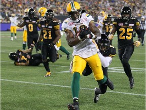 Edmonton Eskimos slotback Cory Watson (18) eludes tackles by the Hamilton Tiger-Cats and runs into score a touchdown during fourth quarter CFL football action in Hamilton, Ont., on Thursday, July 20, 2017.