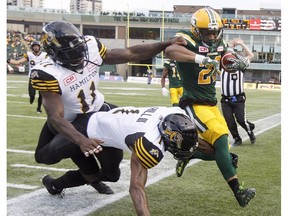 Hamilton Tiger-Cats' Larry Dean (11) and Will Hill (1) run Edmonton Eskimos' LaDarius Perkins (22) out of bounds during first half CFL action in Edmonton, Alta., on Friday August 4, 2017.