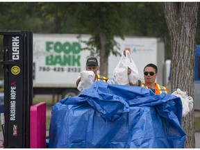 Volunteers transfer food from the drop off locations near the bus stop to a larger container for the Edmonton Food Bank at the Heritage Festival in Hawrelak Park on Monday. As of Wednesday night, the food bank collected 52,694 kilograms of food.