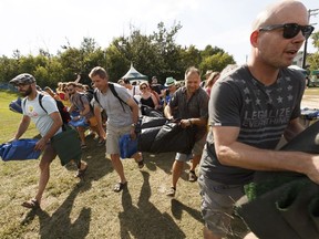 Folk festers scramble to find their tarpaulin spots at the opening of the Edmonton Folk Music Festival at Gallagher Park in Edmonton on Thursday, Aug. 10, 2017.