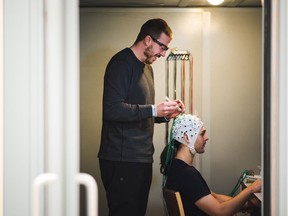 Researcher Kyle Mathewson and master's student Sayeed Kizuk demonstrate the use of EEG technology for studying information processing in the brain.