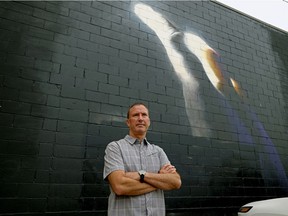 Bob Schilf stands in front the mural painted by an American artist on the exterior of the building at the Track N' Trail store on Whyte Avenue in Old Strathcona. An unknown tagger spray-painted graffiti over the mural, that has since been sprayed over with black paint.