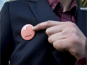 A victim of an alleged sexual assault -- who cannot be identified due to a publication ban -- points to her pin while leaving Calgary Courts Centre in Calgary, Alta., on Tuesday, Nov. 8, 2016. Her alleged attacker Alexander Wagar is being retried for sexual assault after his previous acquittal was overturned when Judge Robin Camp made controversial comments about the victim. File photo.