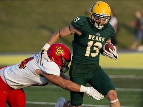 University of Alberta Golden Bears Daniel Bubelenyi (13) fights off a tackle from the University of Calgary Dinos' Boston Rowe (24) at Foote Field, in Edmonton Friday Sept. 1, 2017.