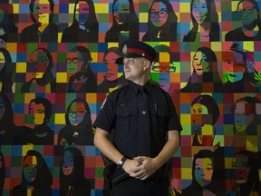 School resource officer Const. Brandon Myhre poses in front of a mural of past and present students at Mother Margaret Mary School, 2010 Leger Rd., in Edmonton Friday, Sept. 29, 2017. Police are ramping up fentanyl education in schools in response to overdoses in the city. Some of the victims have been students.