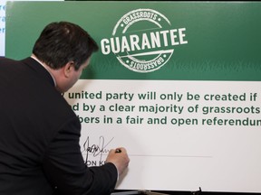 Jason Kenney signs a "grassroots guarantee" during a media conference at the Matrix Hotel about his Progressive Conservative leadership campaign in Edmonton, on Thursday, July 7, 2016.