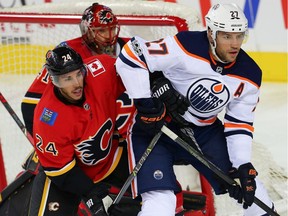 Calgary Flames defenceman Travis Hamonic battles Edmonton Oilers forward Milan Lucic in front of goalie Mike Smith during NHL pre-season action in Calgary on Sept. 18, 2017.