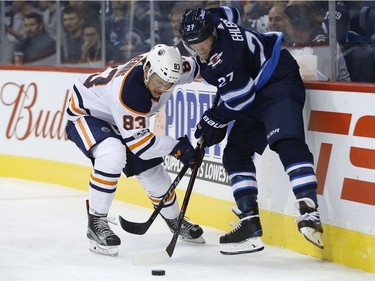 Edmonton Oilers defenceman Matthew Benning, left, and Winnipeg Jets forward Nikolaj Ehlers fight for the puck during NHL pre-season action in Winnipeg on Wednesday, Sept. 20, 2017.