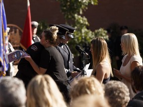 Michael Allin's children receive a memorial flag during the Edmonton Firefighters Memorial Society Remembrance Service that recognizes Edmonton firefighters who have died in the line of duty at Firefighters Memorial Plaza in Edmonton on Monday, Sept. 11, 2017.
