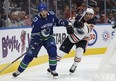 Edmonton's Yohann Auvitu (81) battles Vancouver's Jayson Megna (7) during the second period of a preseason NHL game between the Edmonton Oilers and the Vancouver Canucks at Rogers Place in Edmonton, Alberta on Friday, September 22, 2017.