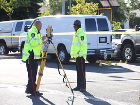 Edmonton police officers stand near a body covered with a white tarp as they investigate an incident near the Westmount McDonald's on Saturday.