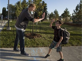 Teacher Drew Urquhart high fives Grade 5 student Asher Doucette, 9, on the first day of school at Ivor Dent School, on Tuesday, Sept. 5, 2017.  Ivor Dent is one of 16 new schools opening this year in the city but unlike new suburban schools, it replaces three aging buildings in northeast Edmonton.