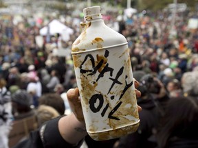 A demonstrator holds up a prop representing dirty oil during a mass sit-in in front of the British Columbia legislature in Victoria, B.C., on Oct. 22, 2012. The death of ducks in tailings ponds in 2008 drew attention from around the world but, despite a change in government, it has happened again.
