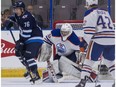 Winnipeg Jets Skyler McKenzie (left) redirects a shot on Edmonton Oilers goalie Stuart Skinner during NHL preseason hockey action at the Young Stars Classic held at the South Okanagan Events Centre in Penticton, BC, September, 9, 2017.