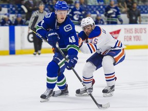 Vancouver Canucks defenceman Olli Juolevi (left) passes the puck off before getting checked by Edmonton Oilers centre Joe Gambardella during NHL rookie tournament action at the Young Stars Classic held at the South Okanagan Events Centre in Penticton, B.C., Sept. 11, 2017.