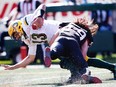 Edmonton Eskimos quarterback Mike Reilly is tackled by Alex Singleton of the Calgary Stampeders during CFL football on Monday, September 4, 2017.