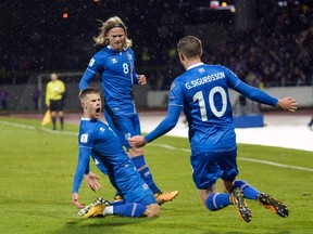 Iceland striker Johann Berg Gudmundsson (left) celebrates his goal against Kosovo with midfielders Birkir Bjarnason (centre) and Gylfi Sigurdsson on Oct. 9.