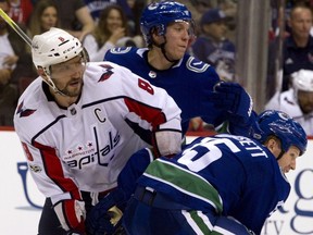 Washington Capitals forward Alex Ovechkin, left is checked by Vancouver Canucks' Markus Granlund, centre and Derek Dorsett, right, during the second period of an NHL hockey game in Vancouver, B.C., on Thursday October 26, 2017.