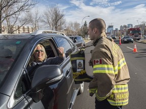 Firefighter Mackenzie Mandrusiak accepts a donation from a motorist in the boot around his neck. Edmonton Fire Fighters held a voluntary toll on 104 Avenue asking drivers to make a donation in a boot in support of Muscular Dystrophy Canada on October 28, 2017. They typically raise around $20,000 in their six hour donation drive.
