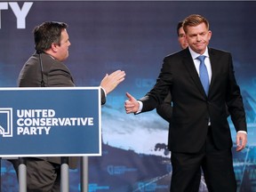 Brian Jean gives a thumbs up on stage after shaking hands with new United Conservative Party Leader Jason Kenney as Doug Schweitzer looks on in Calgary on Oct. 28, 2017.