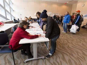 People line up to take part in advance voting in the Heritage Room at City Hall voting stations on Friday Oct. 13, 2017 in Edmonton.