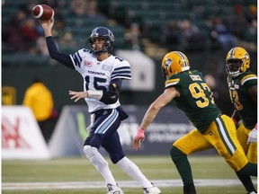 Toronto Argonauts quarterback Ricky Ray, left, throws the ball while being chased by Edmonton Eskimos' John Chick, centre, and teammate Kwaku Boateng during first half CFL football action in Edmonton, Saturday, Oct. 14, 2017.