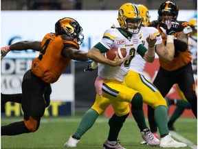 Edmonton Eskimos quarterback Mike Reilly, right, gets away from B.C. Lions' Alex Bazzie during the first half of a CFL football game in Vancouver, B.C., on Saturday October 21, 2017.