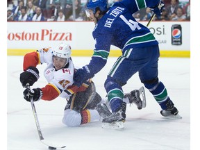 Calgary Flames' Johnny Gaudreau, left, reaches for the puck from his knees in front of Vancouver Canucks' Michael Del Zotto during first period NHL hockey action in Vancouver on Saturday, October 14, 2017.